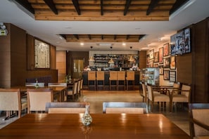 A restaurant with a bar area, wooden furniture, and framed artwork on the walls. - City Hotel Thimphu (Thimphu)
