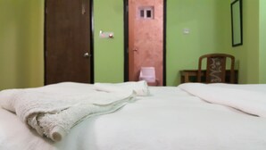 A bed with white linens and a rolled-up white towel. - Hotel Bishram (Pokhara)