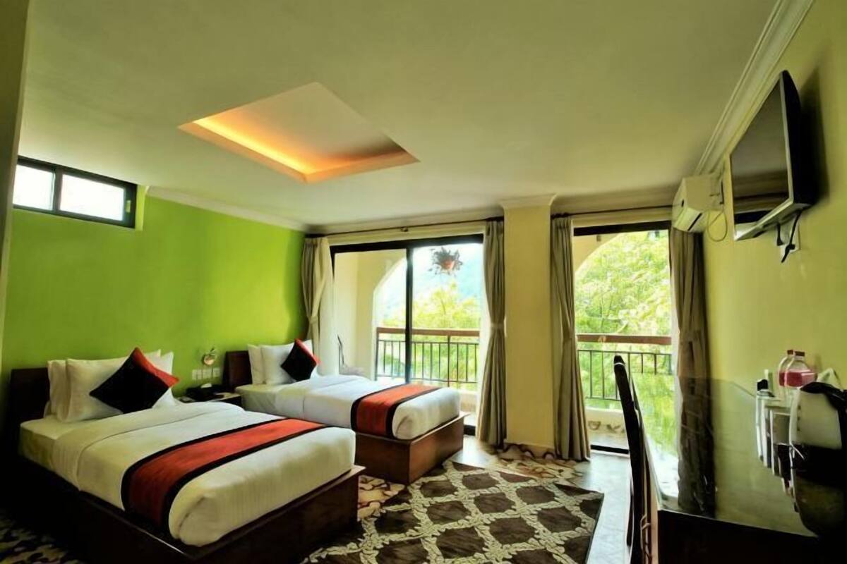 A hotel room with two beds, a TV, a balcony, and a large window.