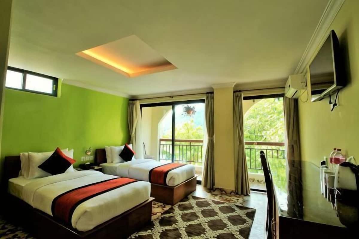 A hotel room with two beds, a TV, a balcony, and a large window.