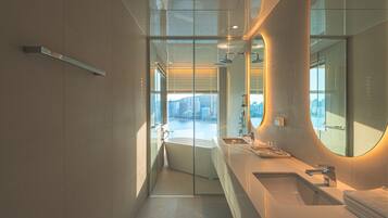 A modern bathroom with a glass-enclosed shower, a large mirror, and a view of the cityscape.