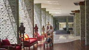 Um hall com paredes de pedra, piso de madeira e mobiliário vermelho.