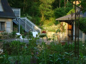 Ein Garten mit einer Treppe, die zu einem Gebäude führt, umgeben von üppigem Grün und verschiedenen Pflanzen.