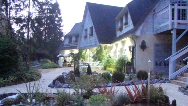 Une cour d’hôtel avec un chemin en pierre, des sièges extérieurs et un escalier menant à l’entrée.