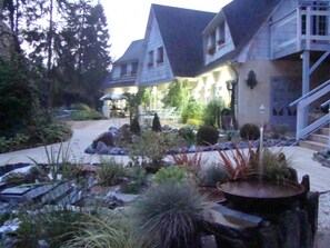 A hotel courtyard with a stone pathway, outdoor seating, and a staircase leading to the entrance. - Le jardin de Saint Jean (Saint-Jean-aux-Bois)