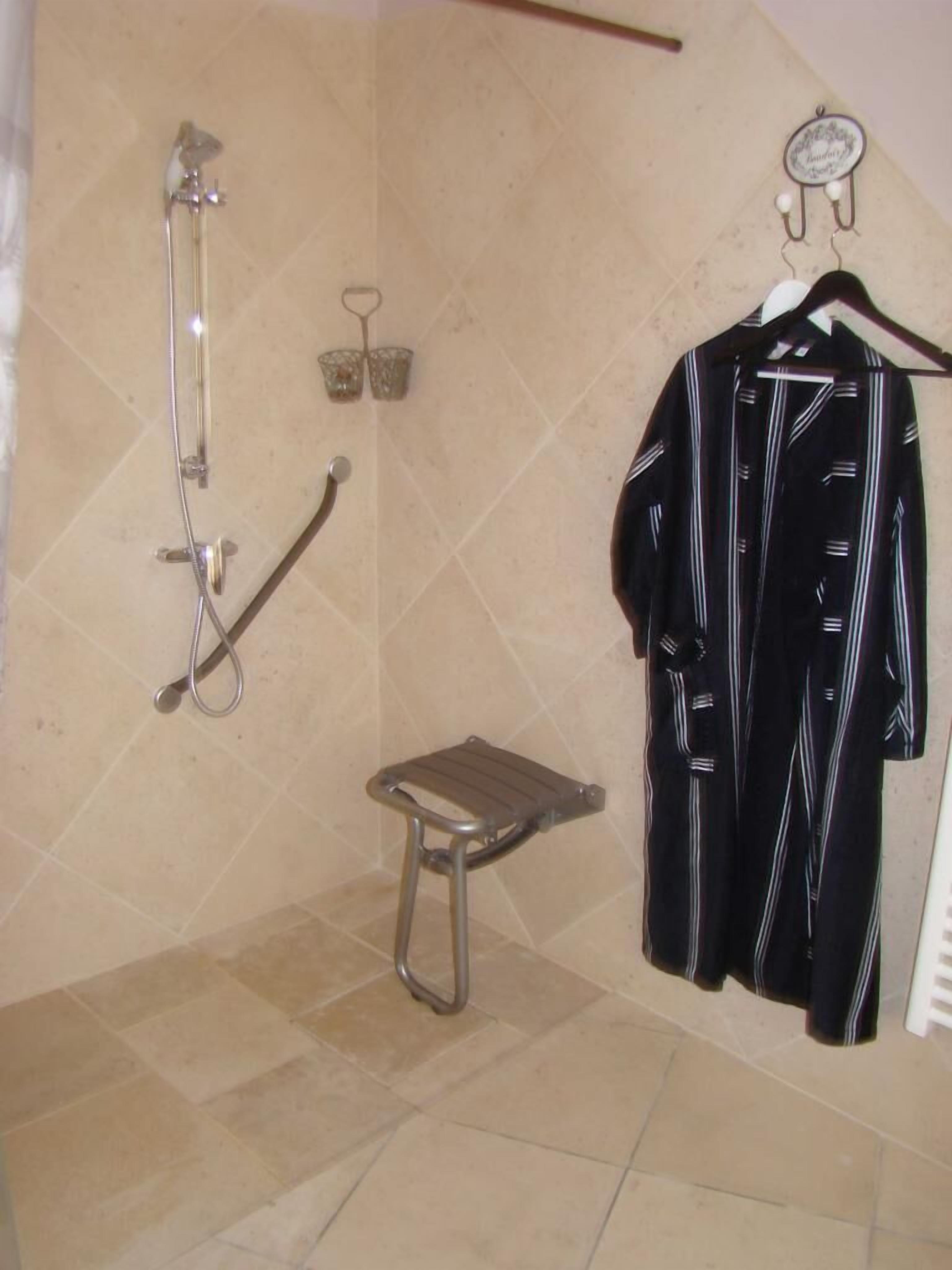 Ein Badezimmer mit Dusche, einem kleinen Hocker und einem Handtuchhalter mit Handtuch.