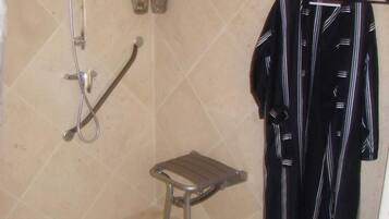 Ein Badezimmer mit Dusche, einem kleinen Hocker und einem Handtuchhalter mit Handtuch.