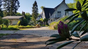 Une allée de gravier mène à une maison dotée d’un toit à pignon bien visible et d’un balcon.