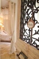 Un dormitorio con cama a dosel, una puerta de madera con reja metálica y un cartel que dice 'Chambre'.
