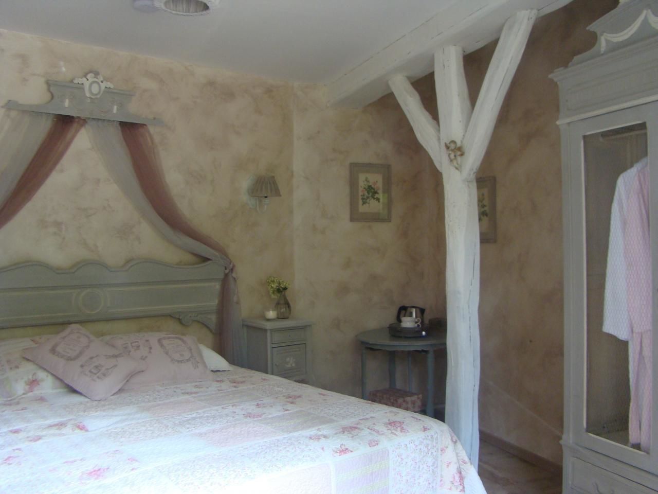 A bedroom with a bed, a nightstand, a small table, and a wardrobe.