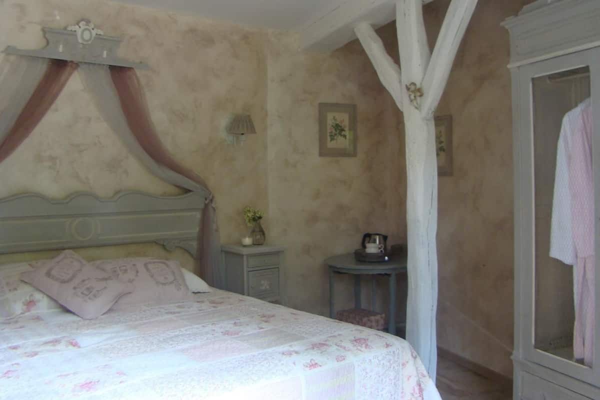 Une chambre à coucher comprenant un lit, une table de chevet, une petite table et une armoire.