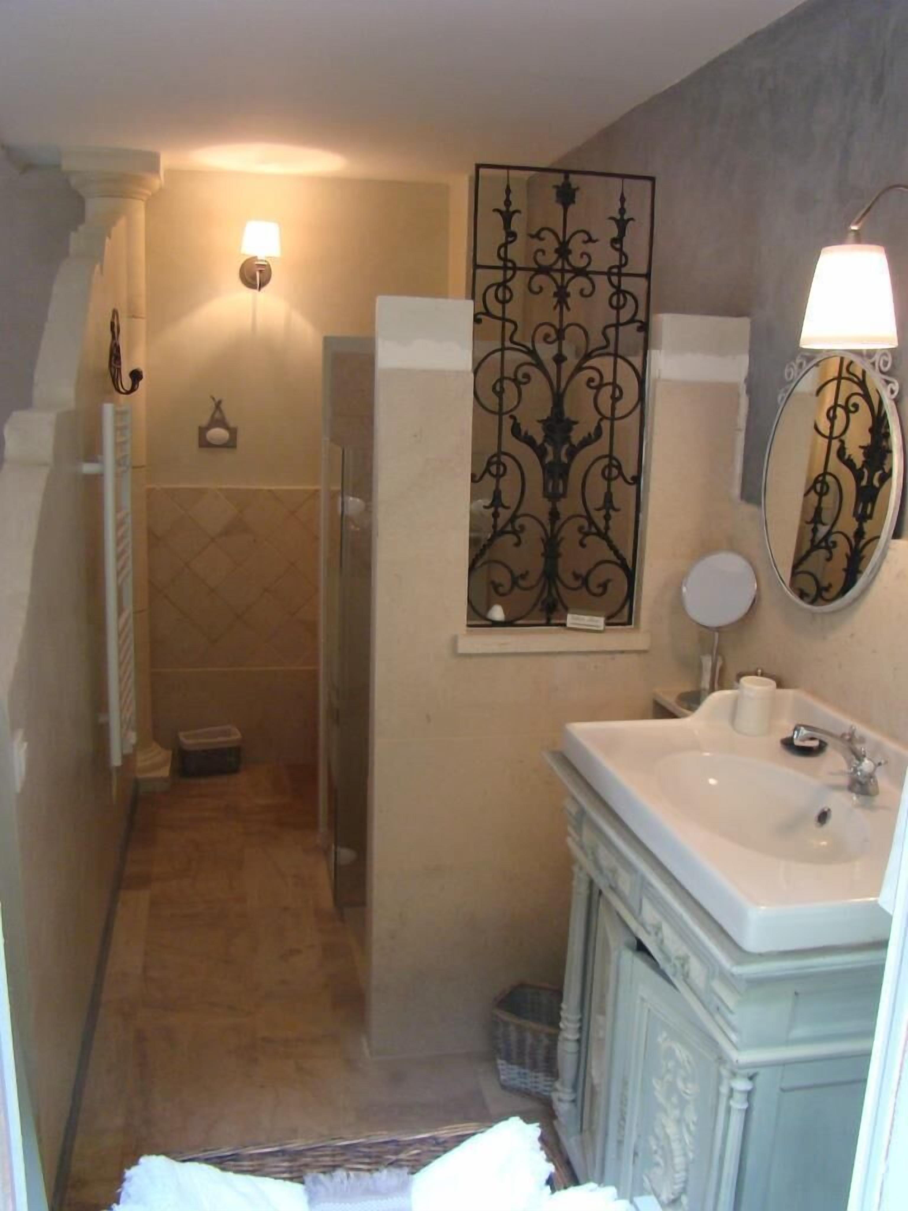 A bathroom with a sink, mirror, and wall-mounted light fixtures.