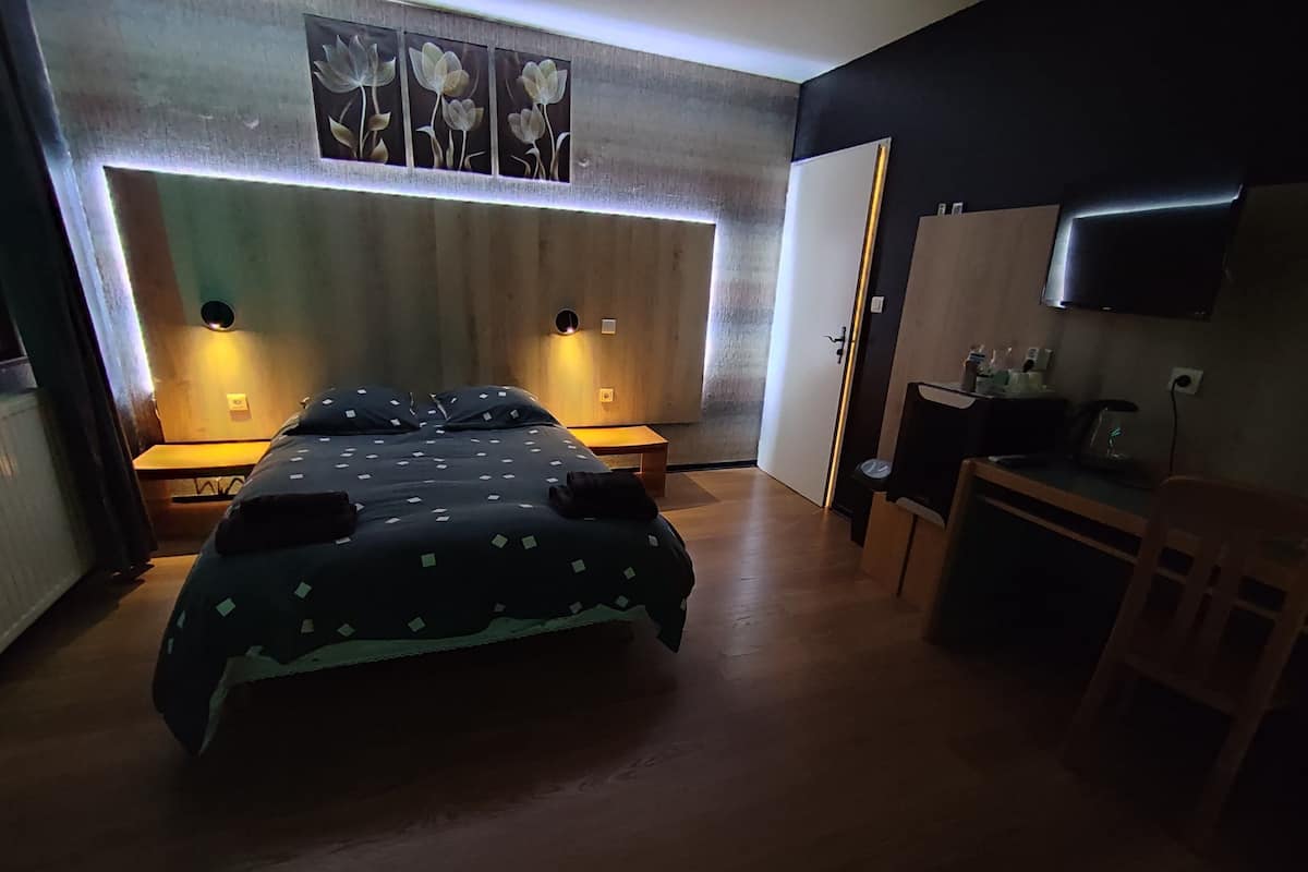 Een slaapkamer met een bed, nachtkastjes, een bureau, een stoel, een televisie en kunst aan de muur.