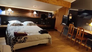 Un dormitorio con cama, mesita de noche, lámpara y escritorio con silla.