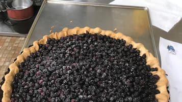 A pie with a flaky crust, filled with blueberries, on a metal tray.