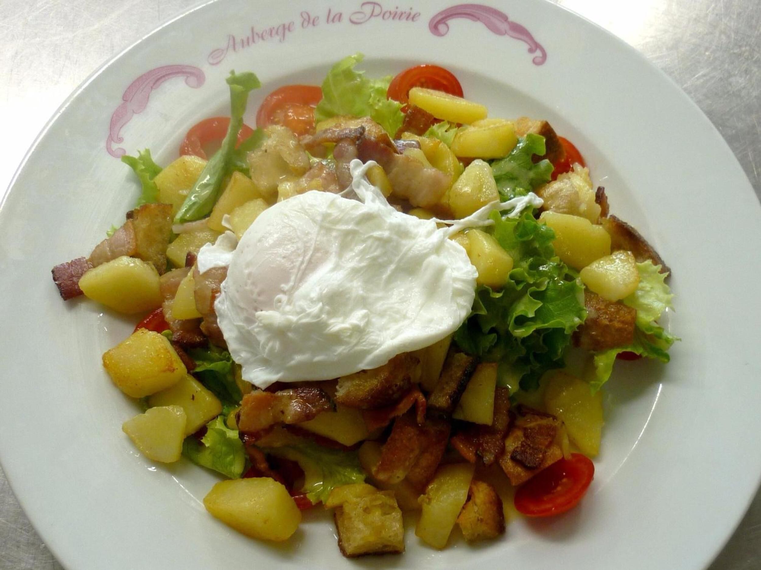 A plate of food with a poached egg, potatoes, lettuce, and tomatoes.