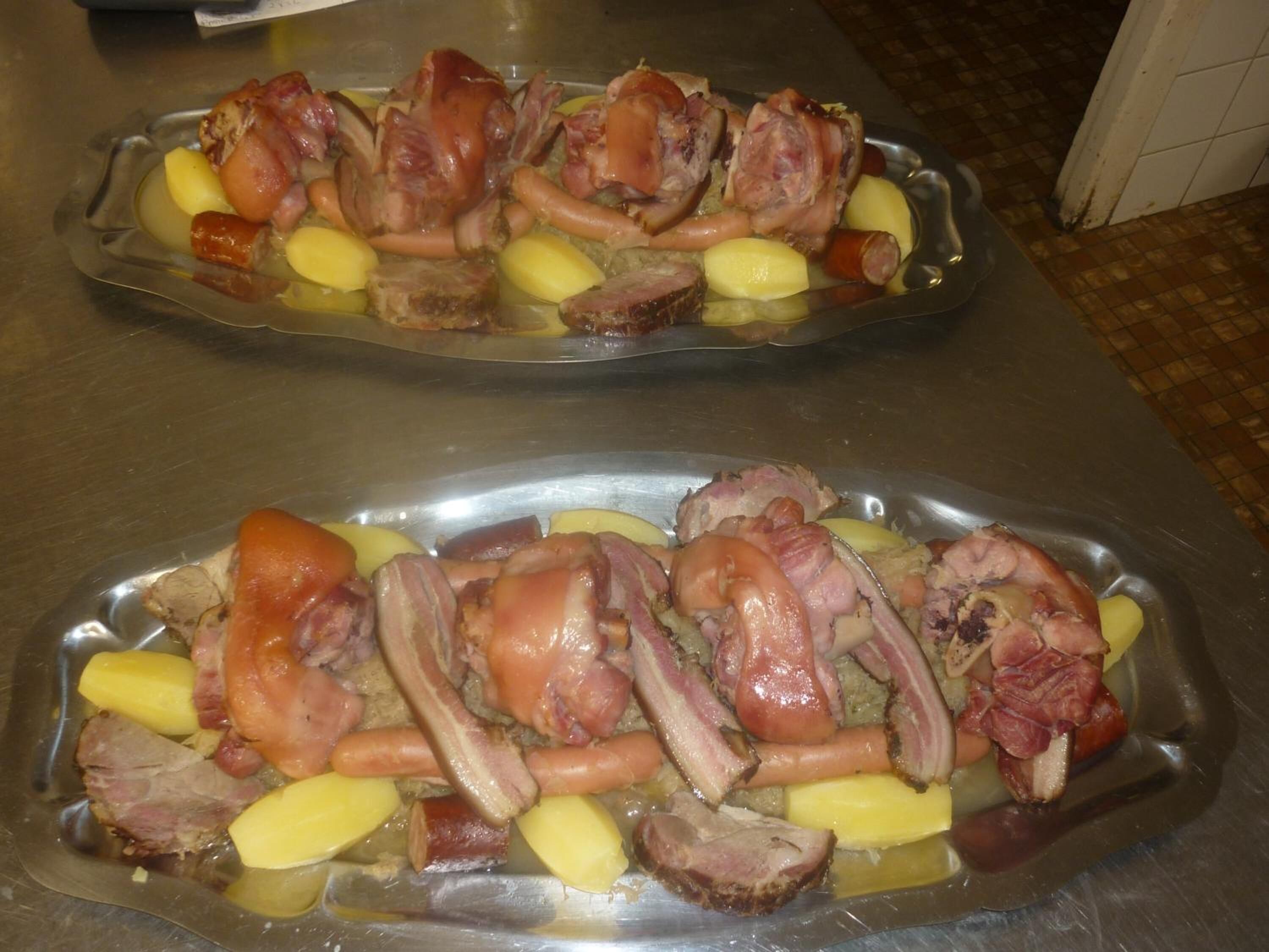 A stainless steel serving dish with roasted pork and potatoes.
