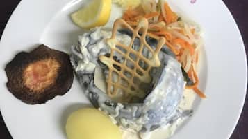 A plate with a variety of food items including a piece of meat, a dollop of sauce, a slice of lemon, and a side of shredded vegetables.