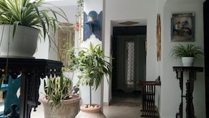 A room with a variety of potted plants, a traditional wooden chair, and a painting on the wall. - El Patio Courtyard House (Tunis)