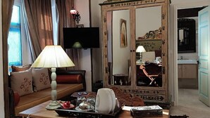 A hotel room with a sofa, a table with a lamp, a mirror, and a television. - El Patio Courtyard House (Tunis)