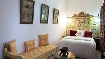 Um quarto com uma cama, um sofá e três quadros na parede.