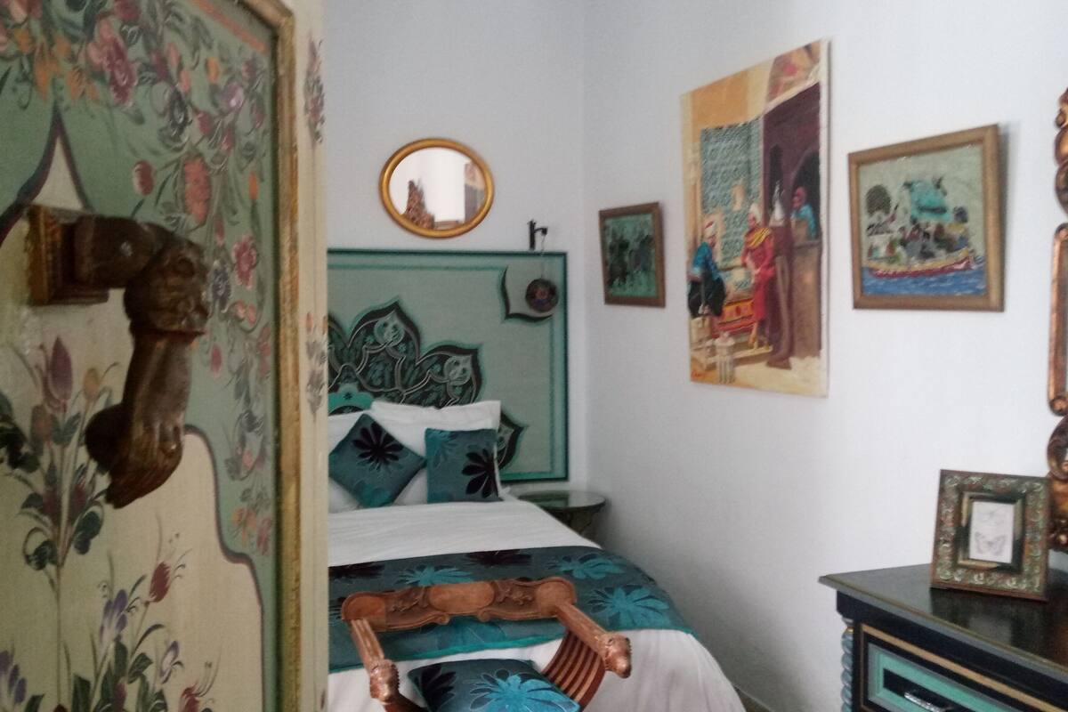 A bedroom with a bed, a mirror, and artwork on the walls.