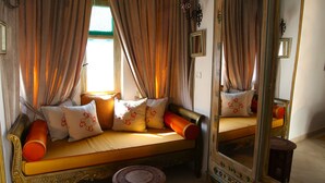A room with a sofa bed, a large mirror, and a small round table. - El Patio Courtyard House (Tunis)