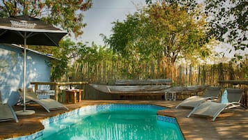 Una piscina al aire libre, sillones reclinables de piscina