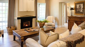 A living room with a fireplace, a sofa, a coffee table, and a chair. - Owner's Cottage at Grande Provence (Franschhoek)