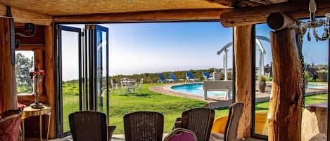 Un patio abierto con mobiliario de mimbre, una piscina y vistas al paisaje.