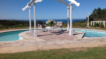 Een buitenzwembad, ligstoelen bij het zwembad