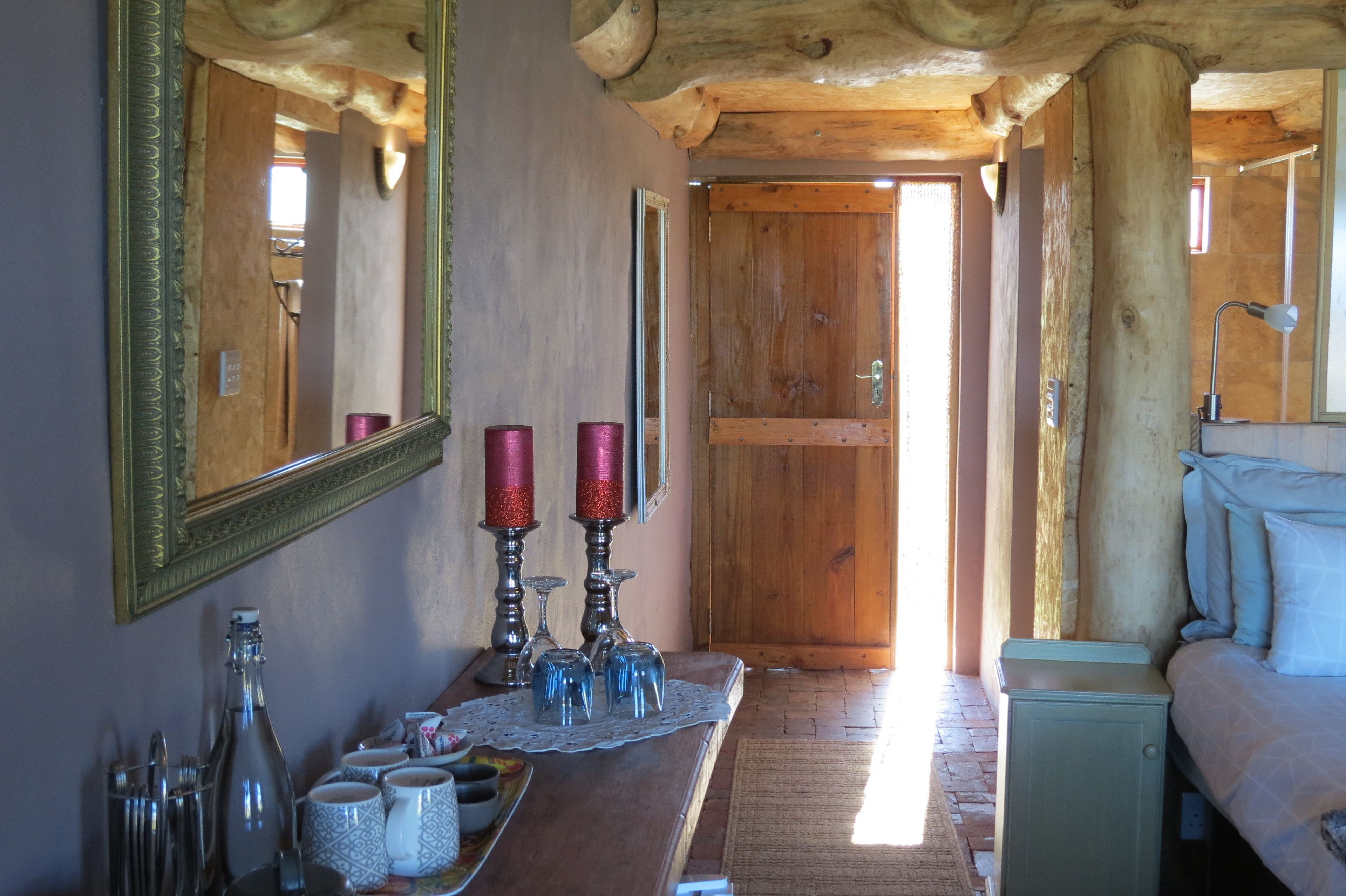 Un intérieur en bois avec un grand miroir, une porte en bois et un lit avec des oreillers.