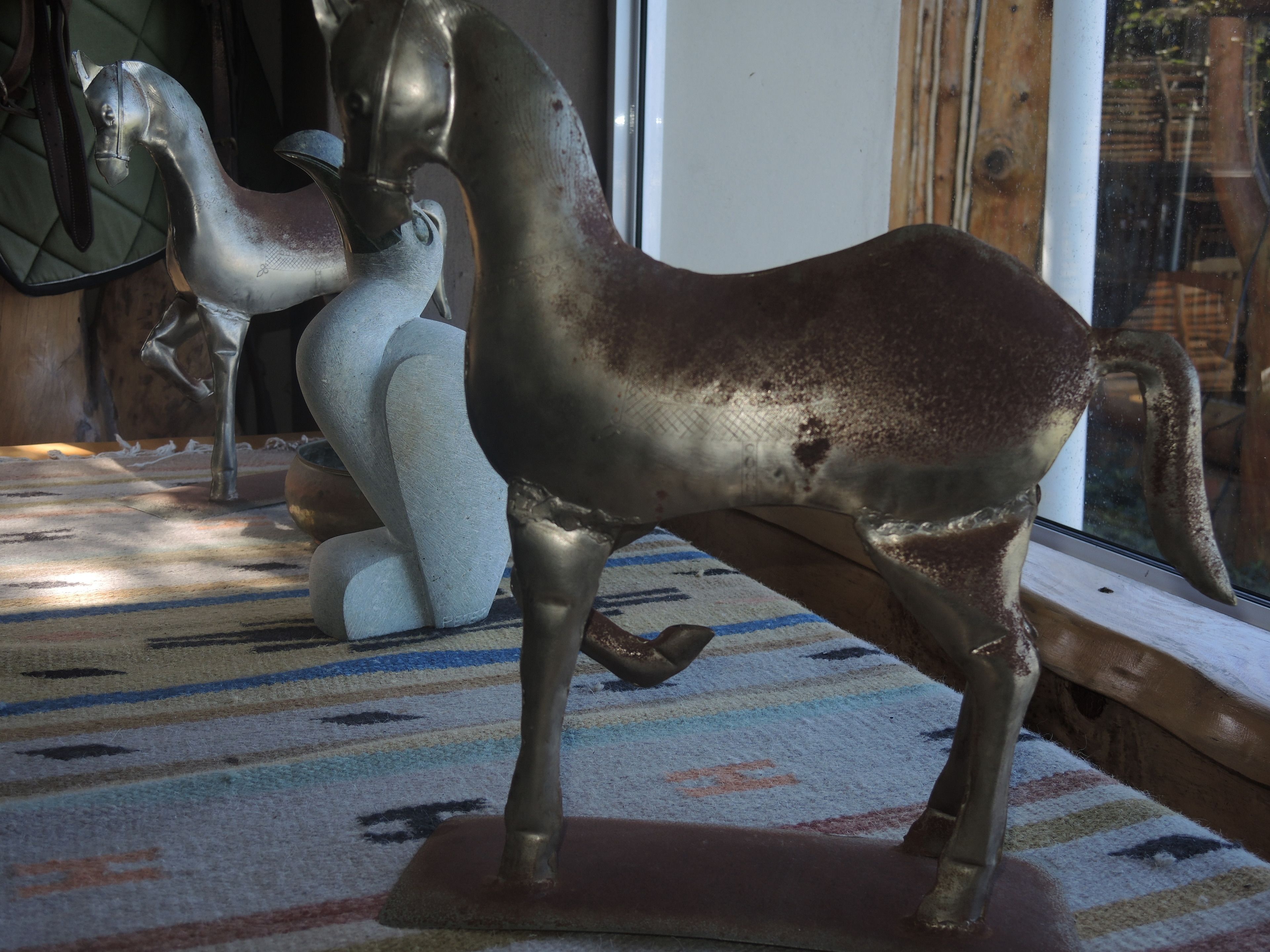 Een metalen beeldhouwwerk van een paard op een kamerkleed met dessin.