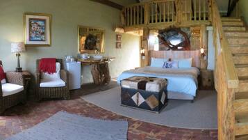 A cozy bedroom with a wooden staircase, wicker furniture, a bed with a blue bedspread, and a rustic decor.