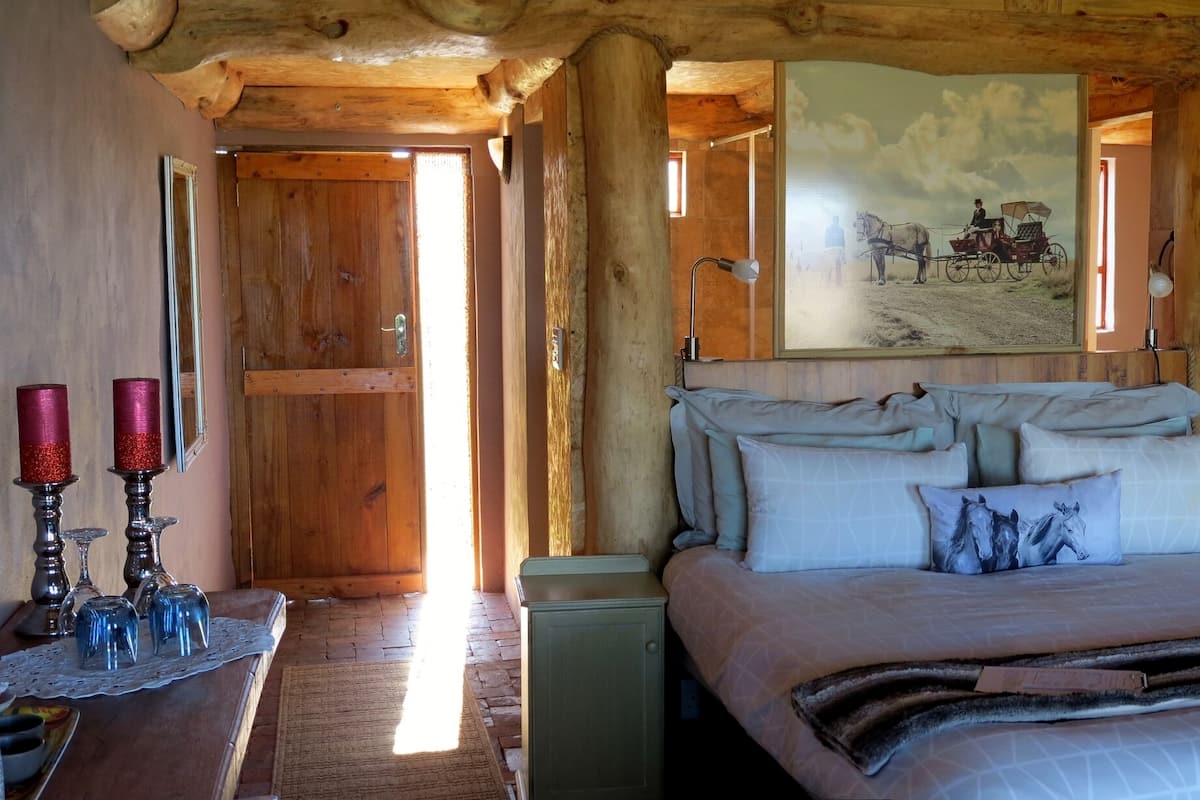 A rustic wooden room with a bed, a wooden ceiling, and a door leading to another room.