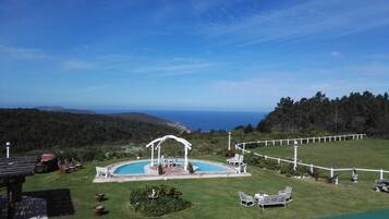 A pool area with a gazebo, lounge chairs, and a view of the ocean.