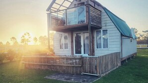 A two-story house with a wooden deck and a glass balcony. - T'Niqua Stable Inn (Plettenberg Bay)