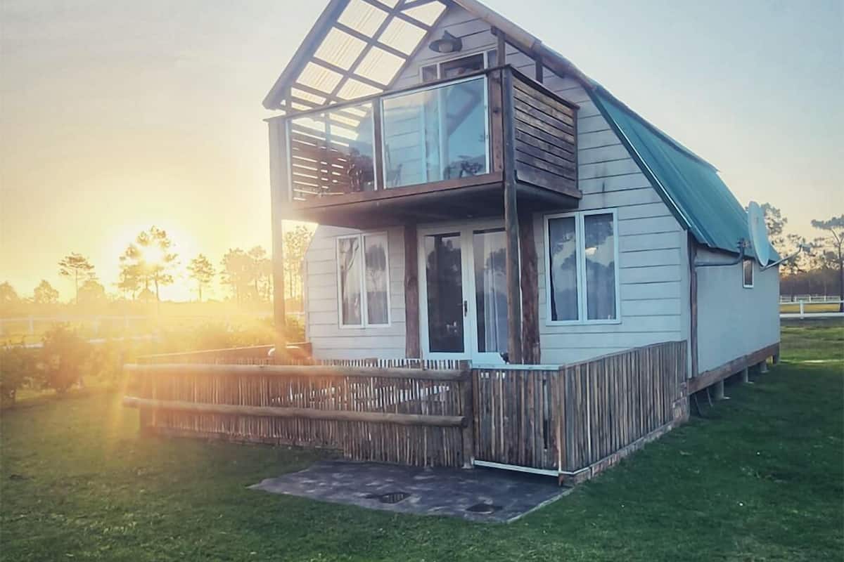A two-story house with a wooden deck and a glass balcony.