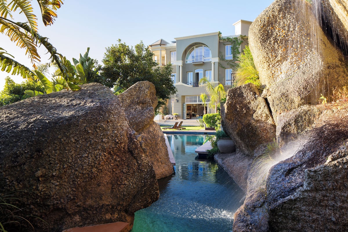 Un resort con piscina rodeada de rocas grandes y palmeras.
