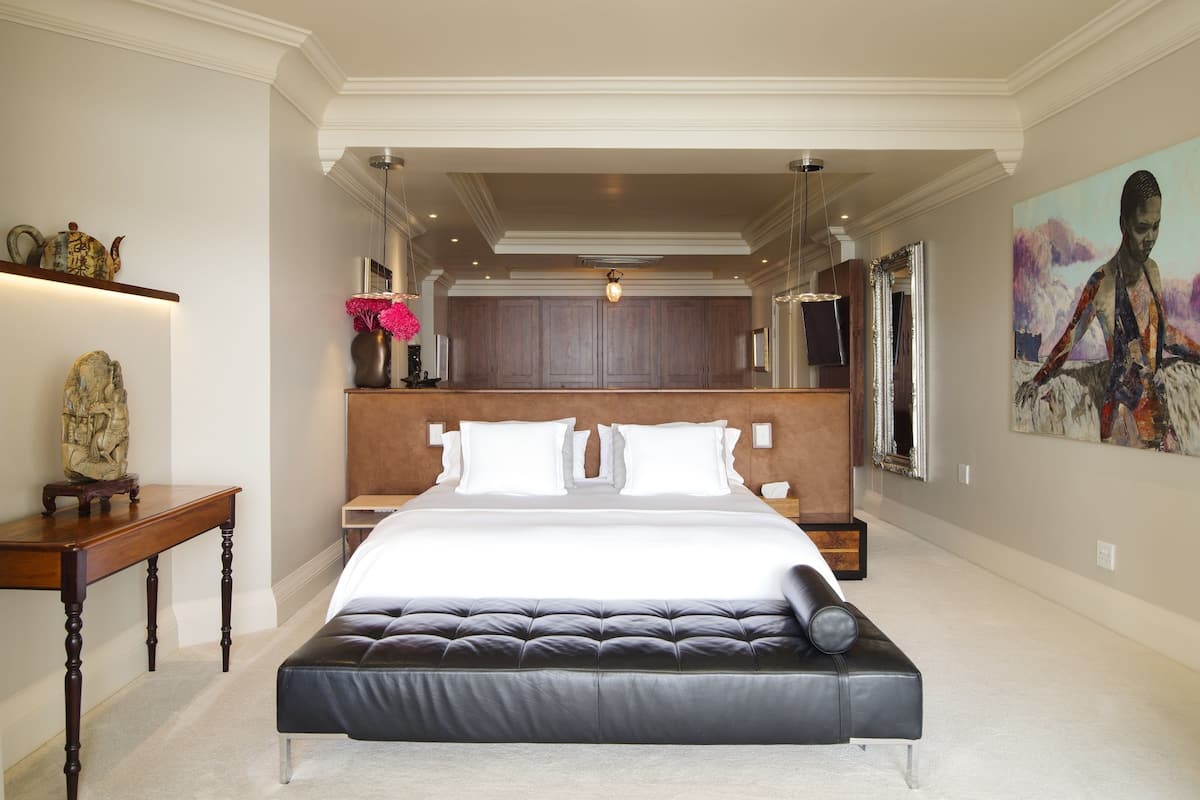 Un dormitorio amplio con una cama grande, una mesita de noche y un jarrón decorativo.
