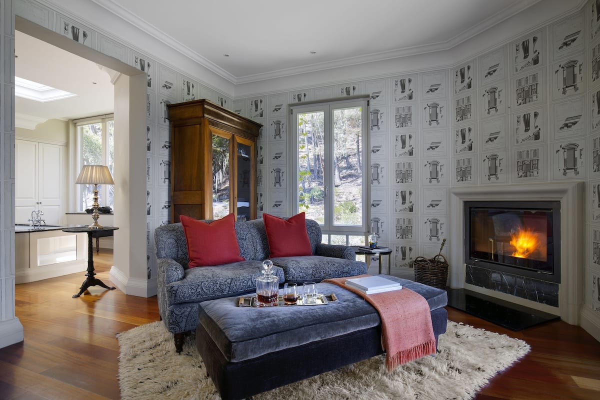 Una sala de estar con chimenea, un sofá, una mesa de centro y una cocina visible a través de una puerta abierta.