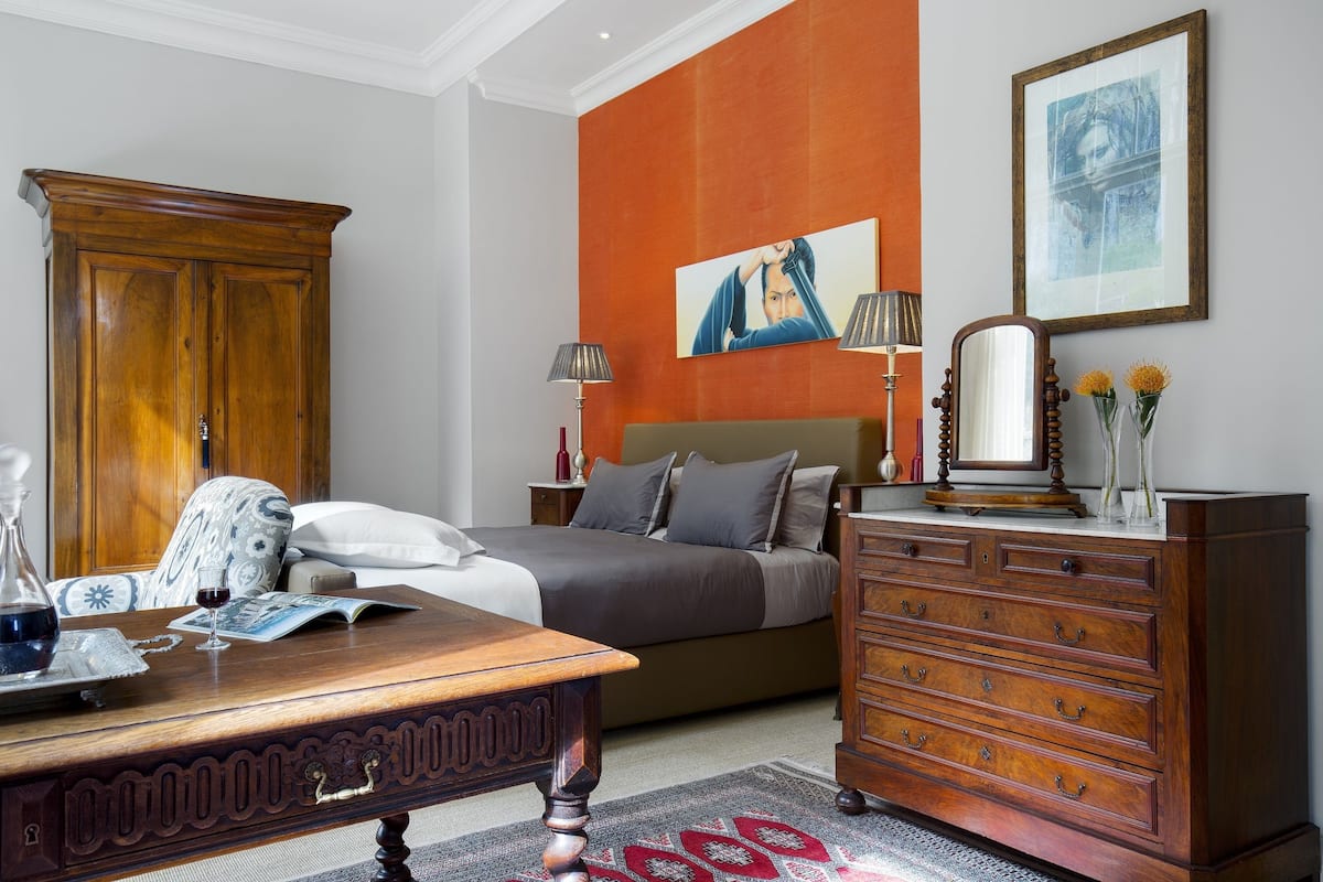 Un dormitorio con cama, cómoda y mesa de madera con una copa de vino.