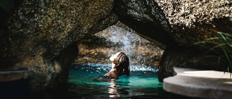 Una piscina al aire libre, sombrillas, sillones reclinables de piscina