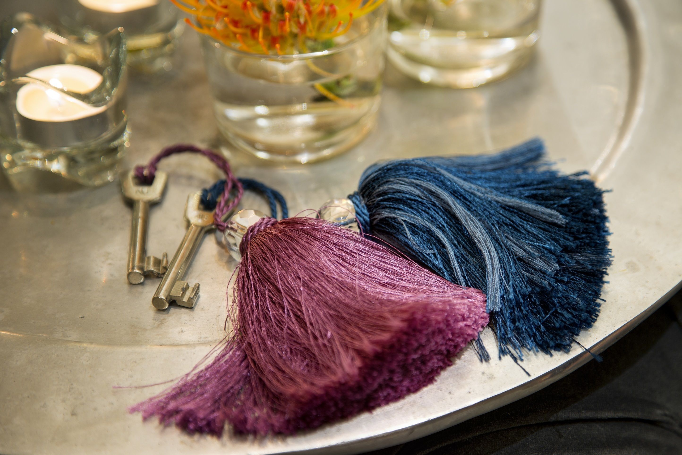 A metal tray with a tassel, keys, and a candle.
