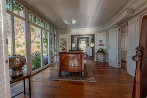 A spacious hallway with wooden flooring, large windows, and a central wooden bench.