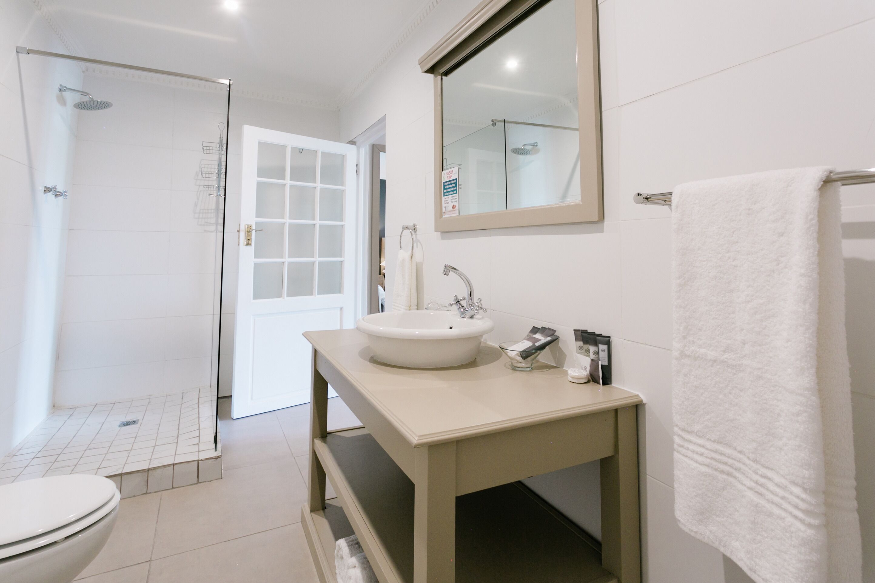 Un baño moderno con ducha, inodoro, lavamanos y un espejo grande.