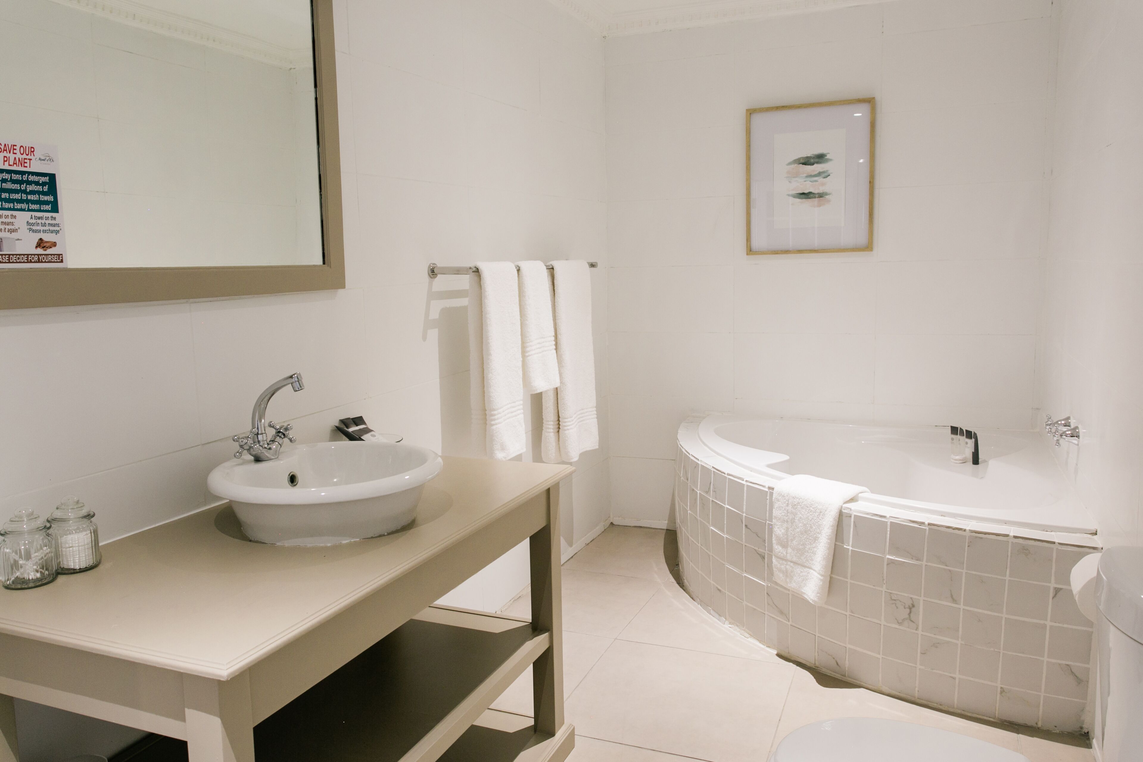 A modern bathroom with a sink, mirror, and bathtub.