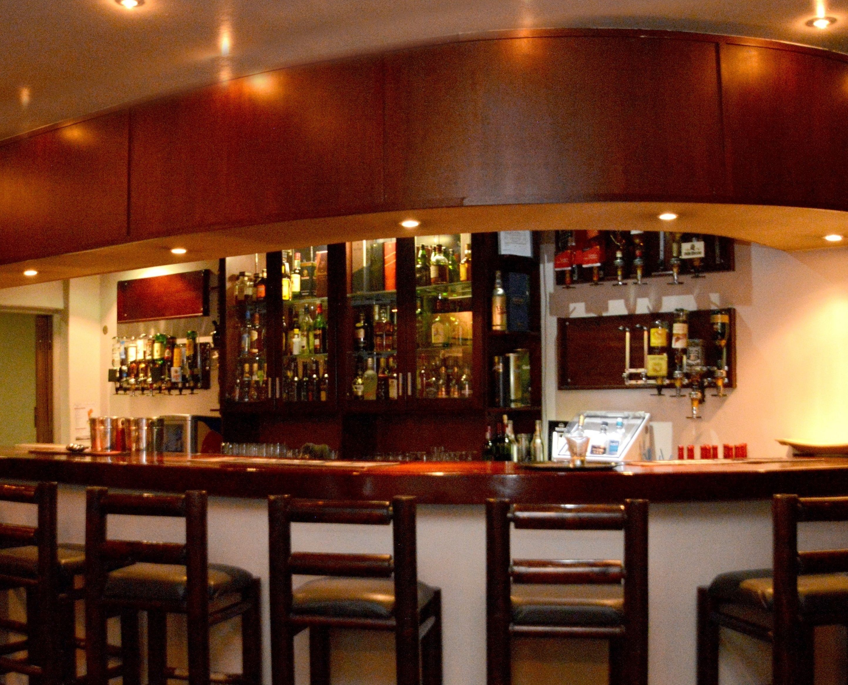 Eine Bar mit Holzsäulen, einer Theke und Barhocker.