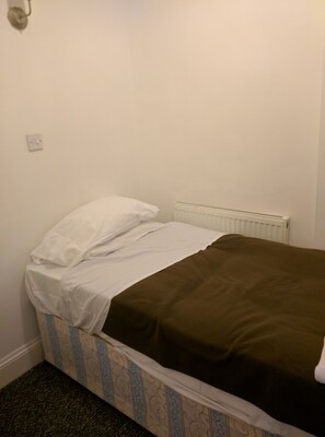 A small, single-bed room with a white headboard, a brown blanket, and a patterned bed skirt. - ABC Bed & Breakfast (London)
