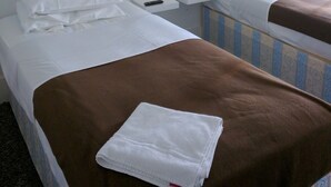Una habitació d'hotel amb dos llits, una tauleta de nit, una làmpada i una finestra.